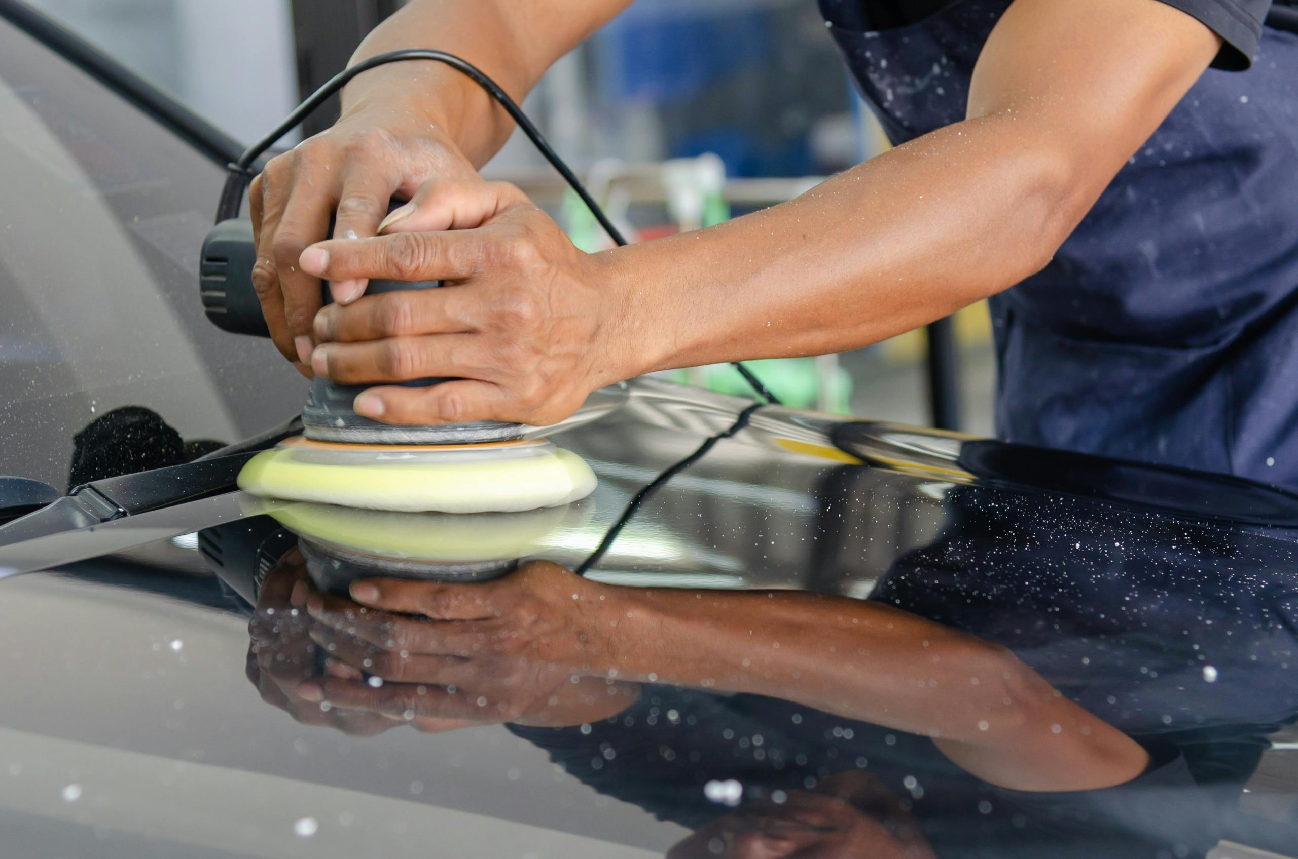 Auto body technician refinishing and polishing vehicle paint in a repair workshop